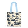 The back of a tote bag featuring a blue pattern with pastoral scenes on a white background.